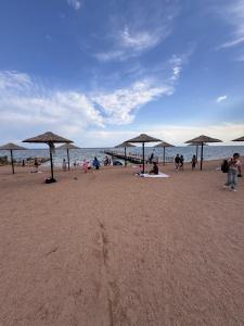 a group of people on a beach with umbrellas at Issyk-kul home in Korumdy