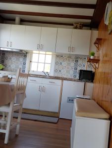 a kitchen with white cabinets and a table and a chair at La cabaña in Cedeira +17 photos