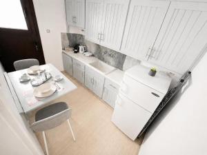 a white kitchen with a table and a white refrigerator at Anthoula House Sarti in Sarti +82 photos