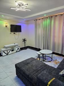 a living room with a couch and a tv and a table at Allan BnB HomaBay in Homa Bay