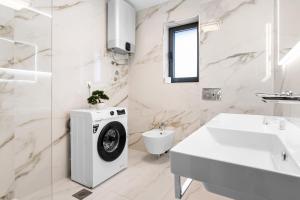 a white bathroom with a washing machine and a sink at Villa Viola in Lovran