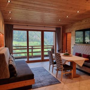 a living room with a table and a large window at Chalet Residence Alpinflair in Ortisei