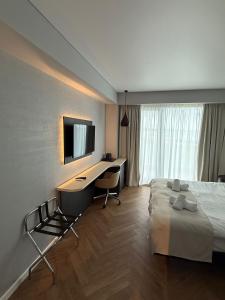 a hotel room with a bed and a desk and a television at Senses Villa By PopDan in Vama Veche +43 photos
