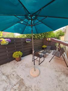 a blue umbrella on a patio with chairs and flowers at Apartment MAIO in Viskovo
