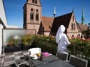 a woman standing on a patio in front of a church at Sofitel Strasbourg Grande Ile in Strasbourg