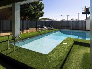 a swimming pool in a yard with grass at ibis Styles Mt Isa Verona in Mount Isa