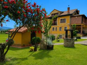 a house with a tree with red flowers in the yard at Apartamentos La Gloria in Santillana del Mar