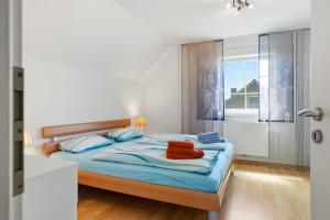 a bedroom with a bed with blue sheets and a window at Friesenperle in Greetsiel