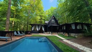 a black house with a swimming pool in a yard at Forest Escape with Jacuzzi & Pool Among the Trees by Destination GREEN Croatia in Ivanec