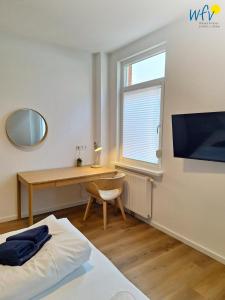 a bedroom with a desk and a bed with a mirror at Stine's Hus Ferienwohnung 2 in Borkum