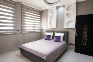 a bedroom with a bed with purple pillows and windows at Tamraght Ocean View in Tamraght Ouzdar