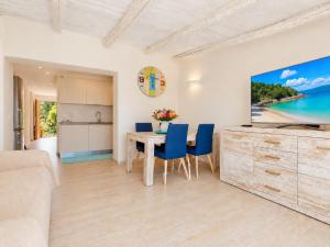 a living room with a table and blue chairs at Sunset Three Shared Pool 100m from the Beach in Baja Sardinia