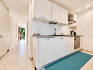 a kitchen with white cabinets and a blue rug at Sunset Three Shared Pool 100m from the Beach in Baja Sardinia