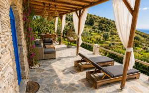 an outdoor patio with chairs and a view of a vineyard at Garden Residence Andros with Sea View & Pool in Gavrio