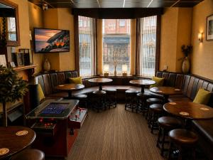 a restaurant with tables and stools in a room with windows at The Kings Cross Hotel in Blackpool