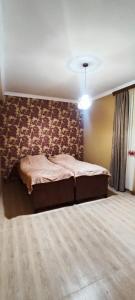 a bedroom with a bed with a floral accent wall at Nino in Kaspi