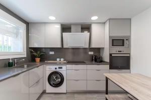 a kitchen with white cabinets and a washing machine at CASA AZUL Blanes in Blanes +18 photos