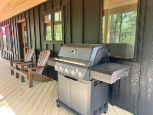 a grill on the porch of a house at Towering Pines Cottage in Saint Germain