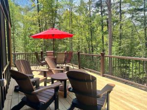 a deck with chairs and a table with a red umbrella at Towering Pines Cottage in Saint Germain