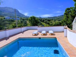 a swimming pool with two lounge chairs on a patio at Villa Jimena in Periana
