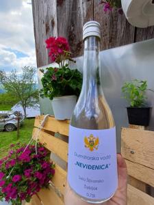a person is holding a bottle of wine at Djedova nova kuca in Žabljak