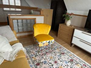 a living room with a yellow chair and a television at Loft de la mer in Sainte-Flavie