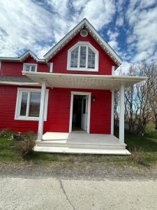 a red house with a porch and a white door at Loft de la mer in Sainte-Flavie