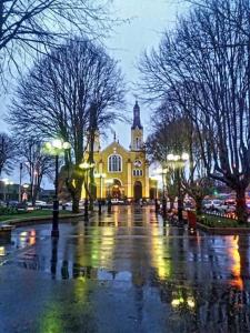 a church on a wet street in front of a building at Hostal Costa Azul in Castro