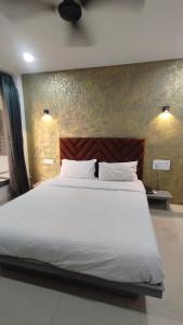 a bedroom with a large bed with white sheets at Hotel 7 Square in Surat +1 photo