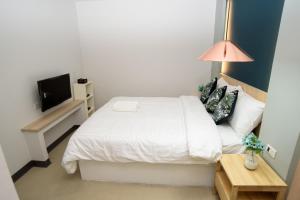 a bedroom with a white bed and a television at MINI Plume Minburi in Min Buri