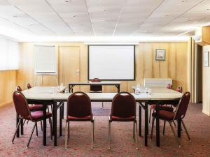 a conference room with tables and chairs and a whiteboard at ibis Châtellerault in Châtellerault