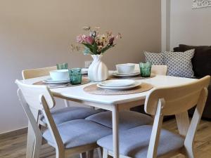 a white dining room table with a white vase with flowers at Marathon Studios & Apartments in Keri +35 photos