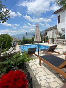 a patio with an umbrella and chairs next to a swimming pool at Hotel Gjirokastra in Gjirokastër