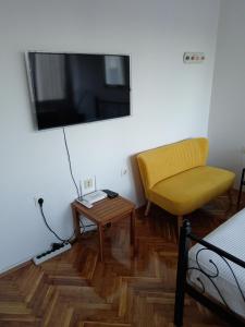 a room with a bed and a chair and a television at Studio apartman LUNA in Vinkovci