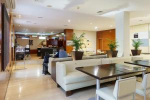 a lobby with couches and tables and a person at Sercotel AB Arganda in Arganda del Rey