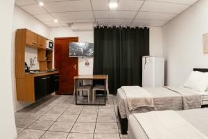 a room with two beds and a table and a kitchen at Large Studios 2km from Vila Germanica in Blumenau