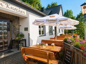 a wooden table with an umbrella and some benches at Pension und Berggasthaus Am Knochen in Geyer