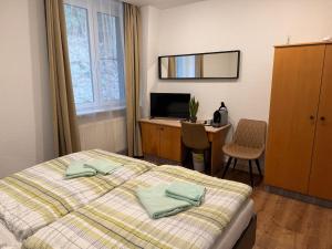 a bedroom with a bed and a desk with a computer at Pension und Berggasthaus Am Knochen in Geyer
