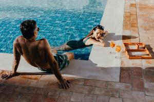a man and a woman sitting next to a swimming pool at Vale Do Lobo Resort in Vale do Lobo