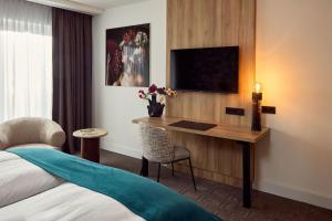 a hotel room with a desk and a bed at Hotel Gladbeck van der Valk in Gladbeck
