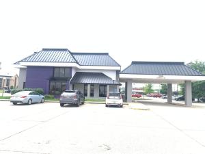 two cars parked in a parking lot in front of a building at Mustang Inn in Paducah