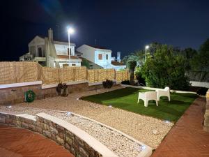 a garden with two white chairs and a fence at night at Bed and Breakfast Villa Teis in Quartu SantʼElena