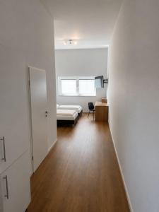 a white room with a bed and a desk at Gauaz Boardinghouse in Maisach