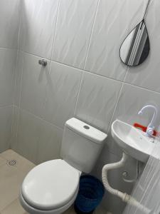 a bathroom with a white toilet and a sink at Quarto Selva in Itaquatiara