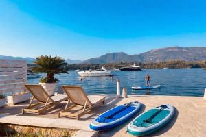 a group of chairs and surfboards on a dock with boats at Lavander Apartment W Pool and Private Beach in Tivat