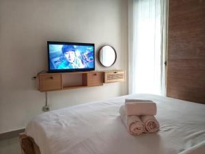 a bedroom with a bed with a television on the wall at Homestay Omah in Tabanan