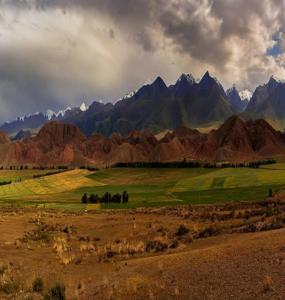 a field with mountains in the background with a cloudy sky at Guest House Eltin in Bokonbayevo
