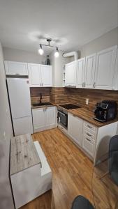 a kitchen with white cabinets and a wooden floor at Elena Relax Apartment in Varna City