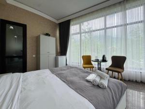 a bedroom with a large bed with two chairs and a table at Panoramic Mountains Hotel Guba in Qırızdǝhnǝ