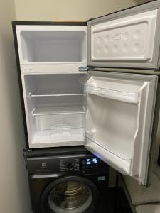 an open refrigerator next to a washing machine at Acapulco Liepaja in Liepāja